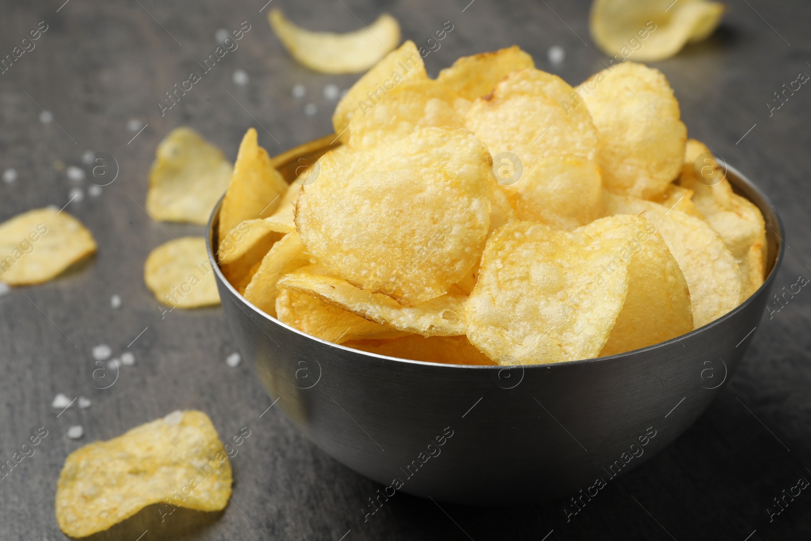 Photo of Delicious crispy potato chips in bowl on table, closeup