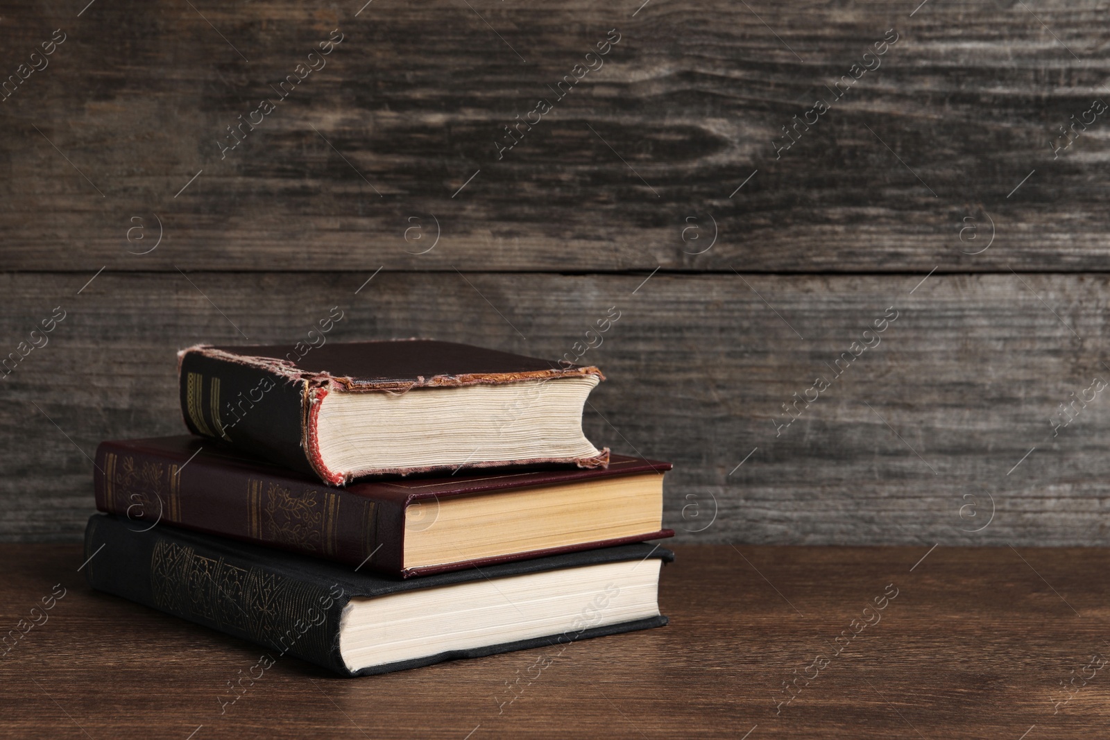 Photo of Stack of old hardcover books on wooden table, space for text