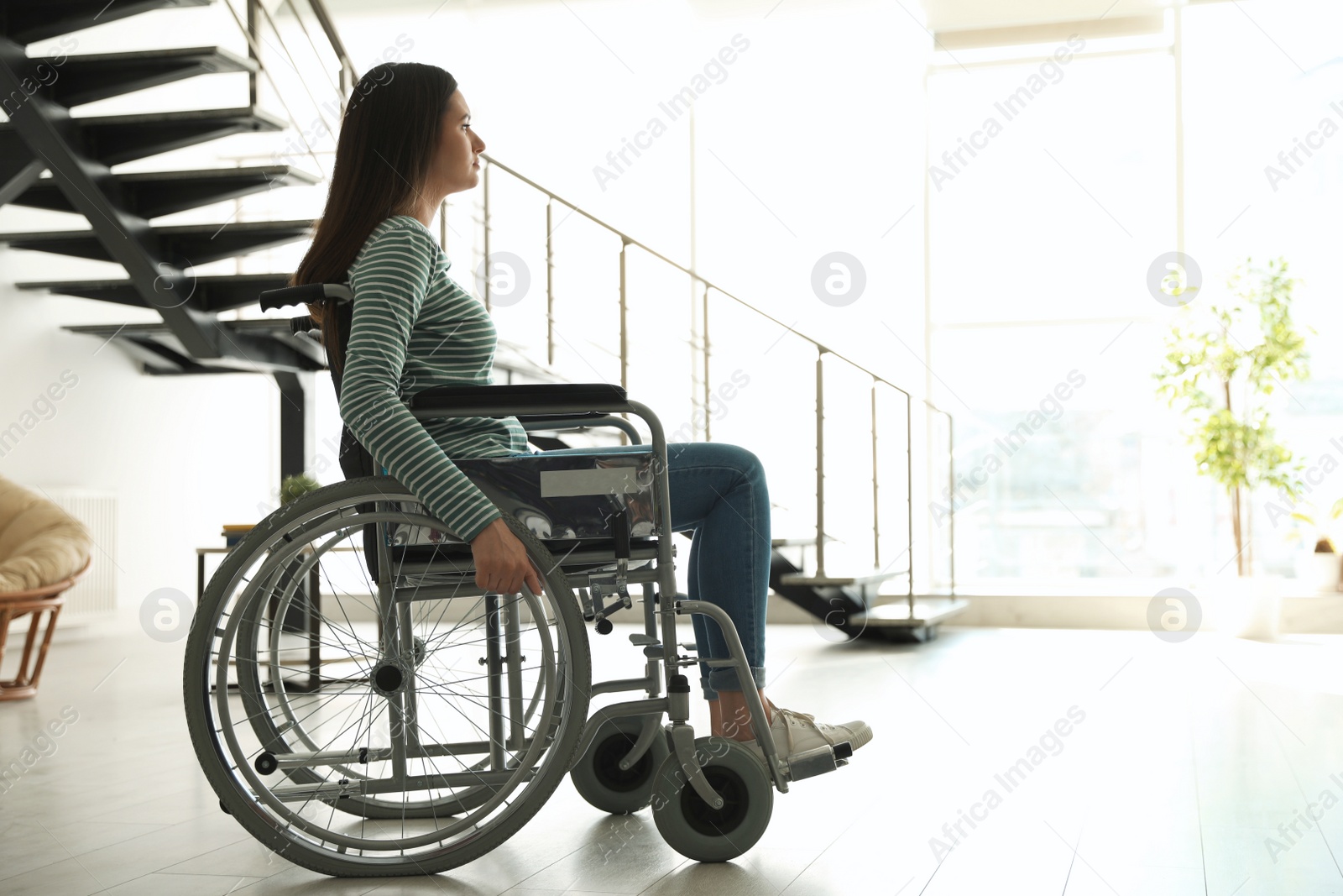 Photo of Young woman in wheelchair indoors. Space for text