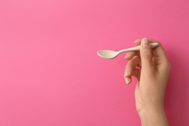 Photo of Woman holding empty small spoon on color background, closeup. Space for text