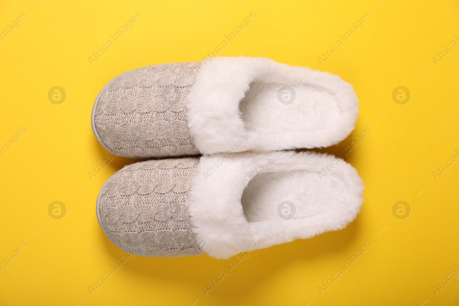 Photo of Pair of beautiful soft slippers on yellow background, top view