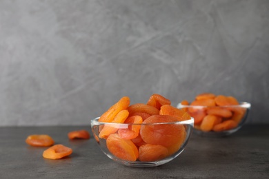 Photo of Bowl with dried apricots on grey table, space for text. Healthy fruit