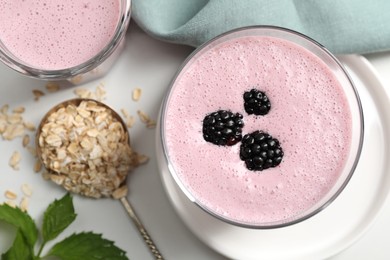Photo of Glasses of blackberry smoothie and oatmeal on white table, flat lay