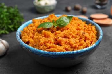 Photo of Bowl of tasty sweet potato puree on grey table