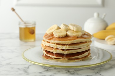 Photo of Delicious pancakes with bananas and honey on white marble table, closeup. Space for text