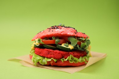 Photo of Tasty pink vegan burger with vegetables, patty and microgreens on light green background, closeup