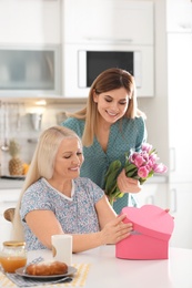 Photo of Daughter congratulating happy mature woman on Mother's Day at home