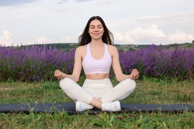 Photo of Smiling woman practicing yoga near lavender outdoors