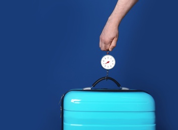 Photo of Man weighing stylish suitcase against color background, closeup. Space for text