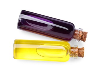 Photo of Glass bottles with yellow and purple food coloring on white background, top view
