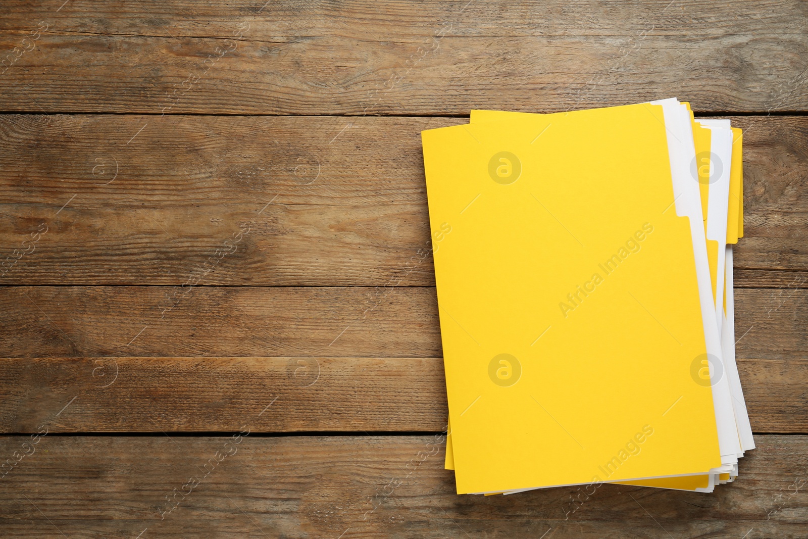 Photo of Yellow files with documents on wooden table, top view. Space for text
