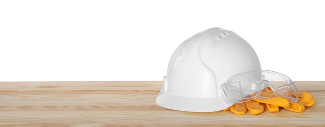 Photo of Hard hat, gloves and goggles on wooden table against white background. Safety equipment