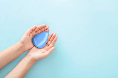 Image of Woman holding water drop on light blue background, top view with space for text. Ecology protection