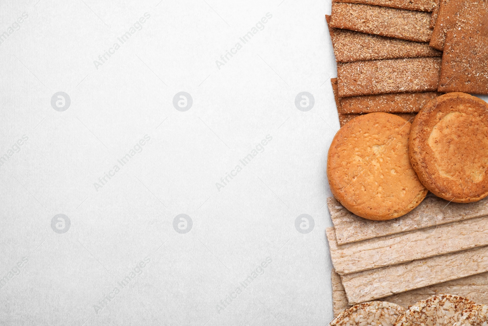 Photo of Rye crispbreads, rice cakes and rusks on white table, flat lay. Space for text
