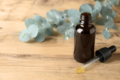 Bottle of essential oil and eucalyptus on wooden table