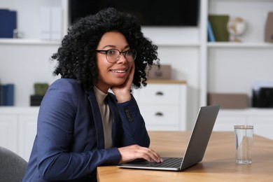 Young woman working on laptop at table in office