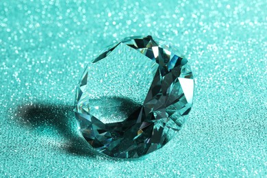 Photo of Beautiful dazzling diamond on green glitter background, closeup