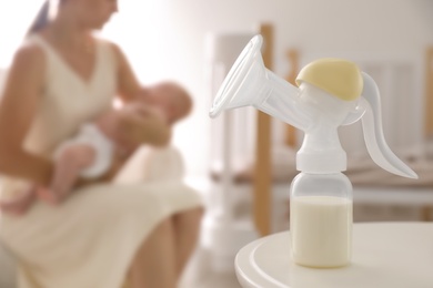 Photo of Mother and little baby indoors, focus on table with breast pump