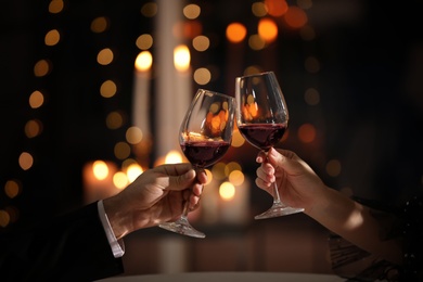 Photo of Couple clinking glasses at Valentine's day dinner in restaurant, closeup