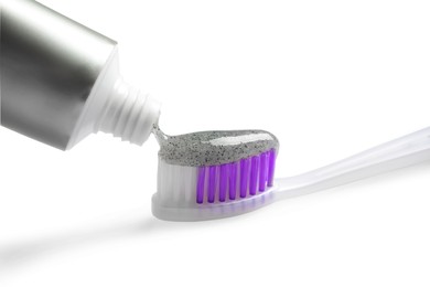 Photo of Tube of charcoal toothpaste and brush on white background