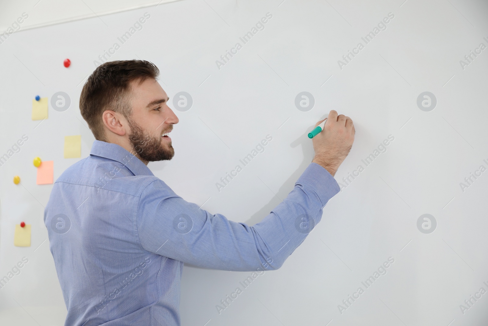 Photo of Portrait of young teacher writing on whiteboard in classroom