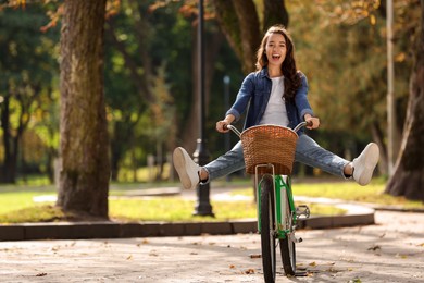 Photo of Young woman riding bicycle in park, space for text