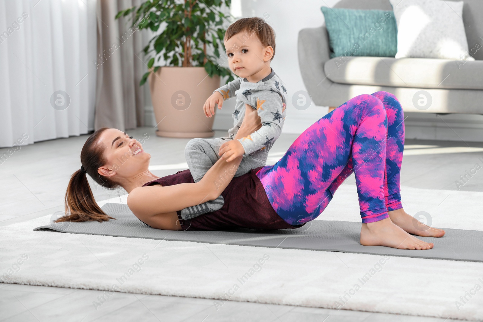 Photo of Woman doing fitness exercises together with son at home