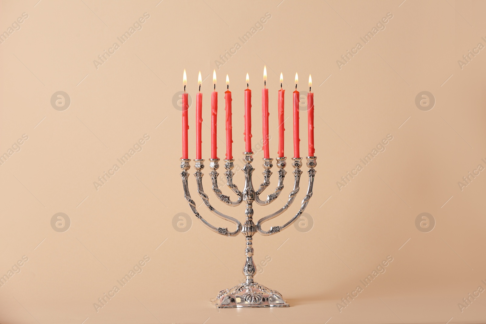 Photo of Silver menorah with burning candles on beige background. Hanukkah celebration