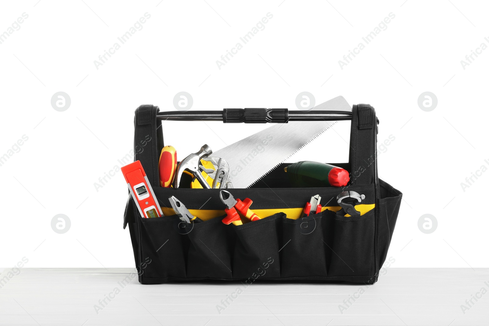 Photo of Bag with different tools on wooden table against white background