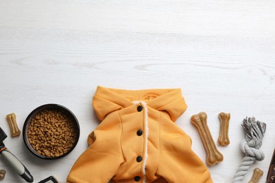 Photo of Flat lay composition with dog clothes, food and accessories on white wooden table. Space for text