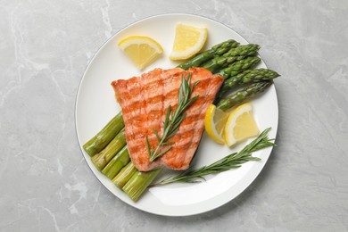 Photo of Tasty grilled salmon with asparagus, lemon and rosemary on light grey table, top view