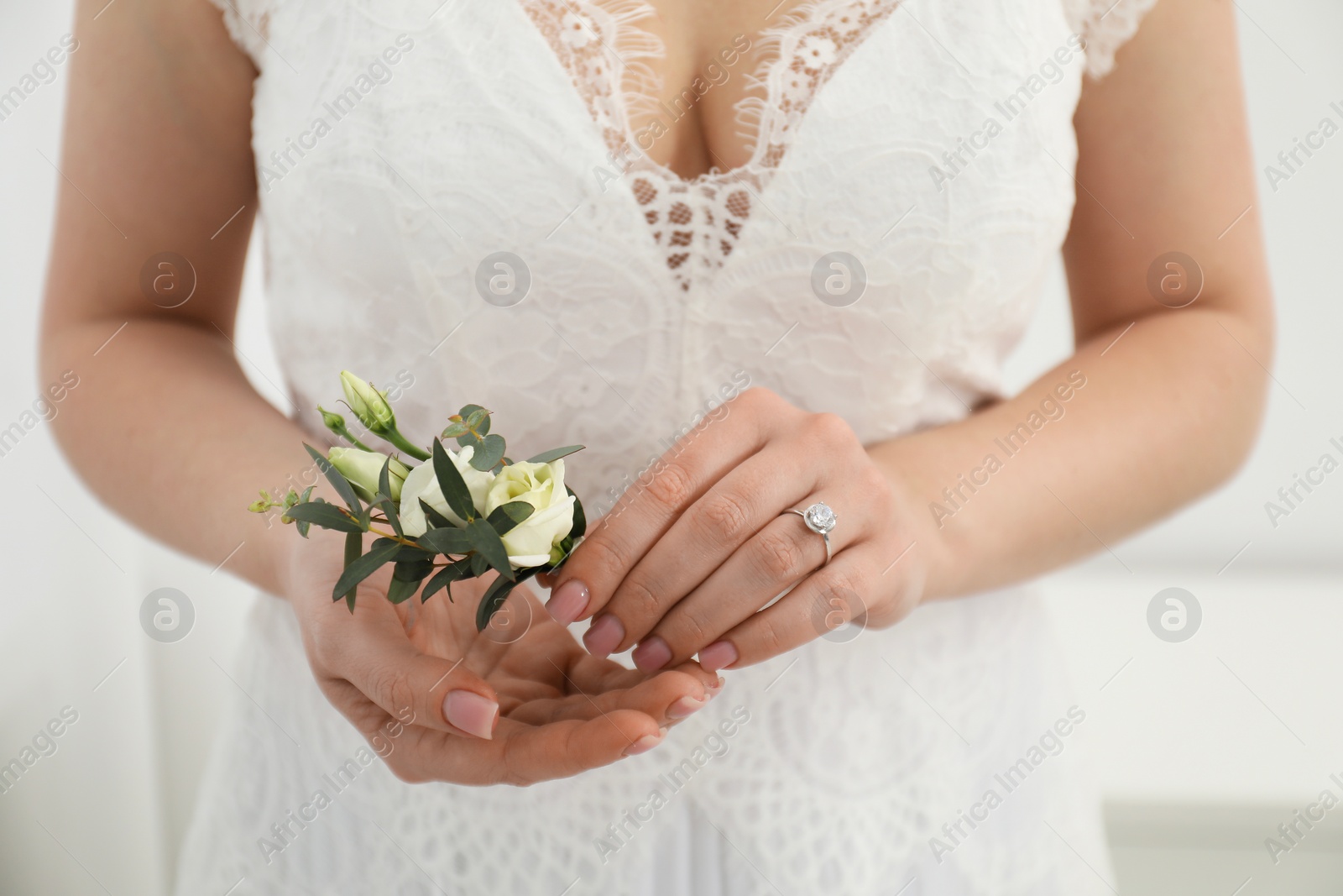 Photo of Bride holding boutonniere for her groom on blurred background, closeup