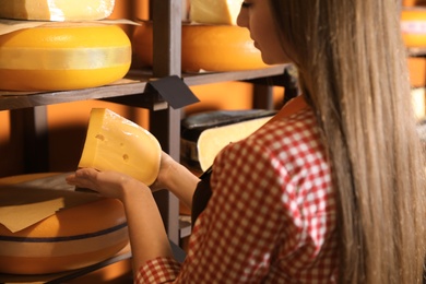 Seller with piece of delicious cheese near rack in store