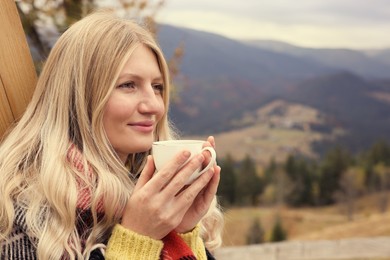 Photo of Young woman with cup of hot drink in mountains. Space for text