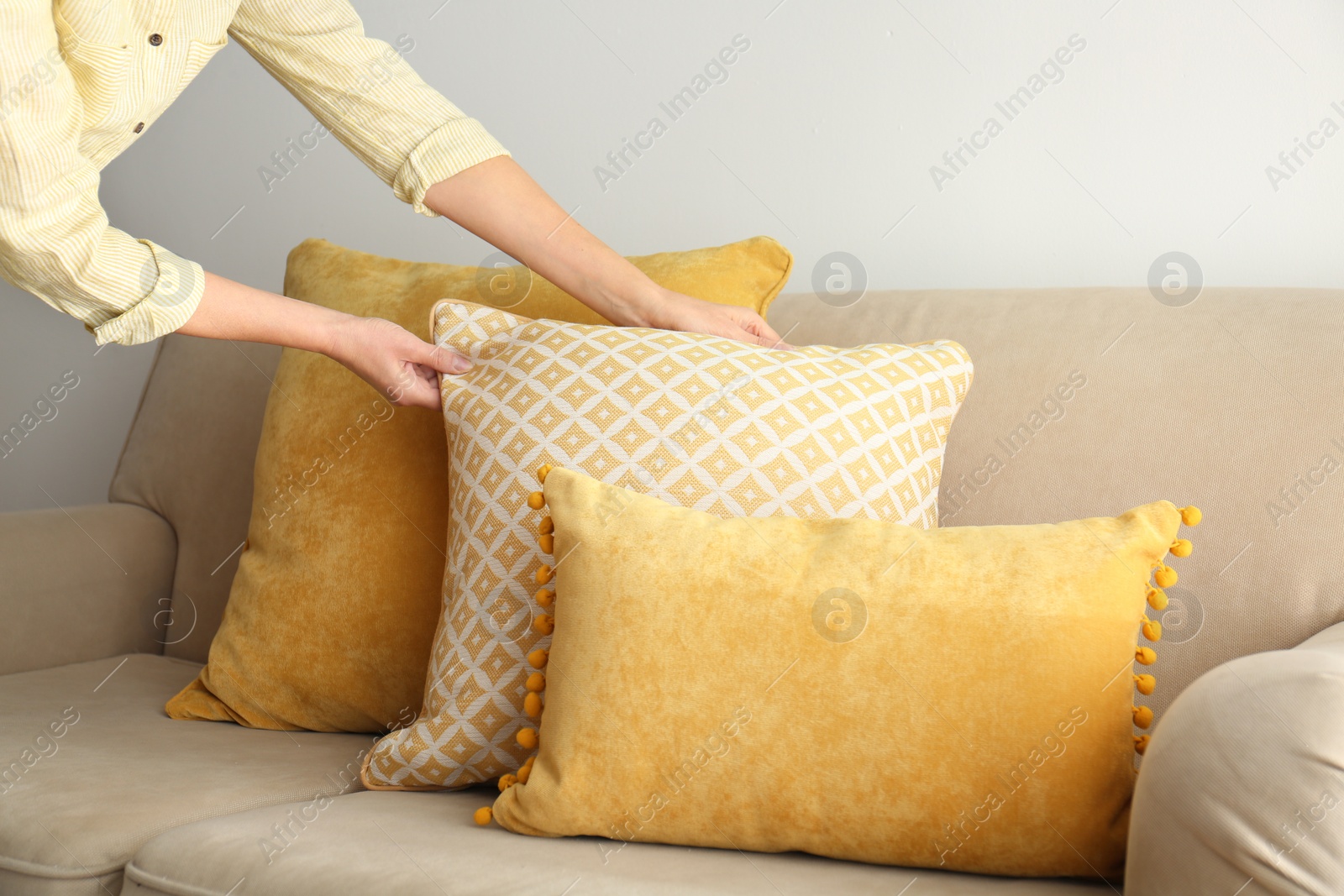 Image of Woman arranging pillows on sofa, closeup view. Interior design