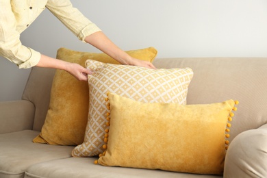 Image of Woman arranging pillows on sofa, closeup view. Interior design