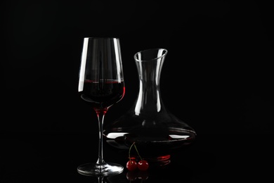 Photo of Delicious cherry wine and ripe juicy berries on black background