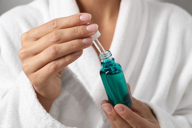 Photo of Woman with bottle of cosmetic serum and pipette, closeup