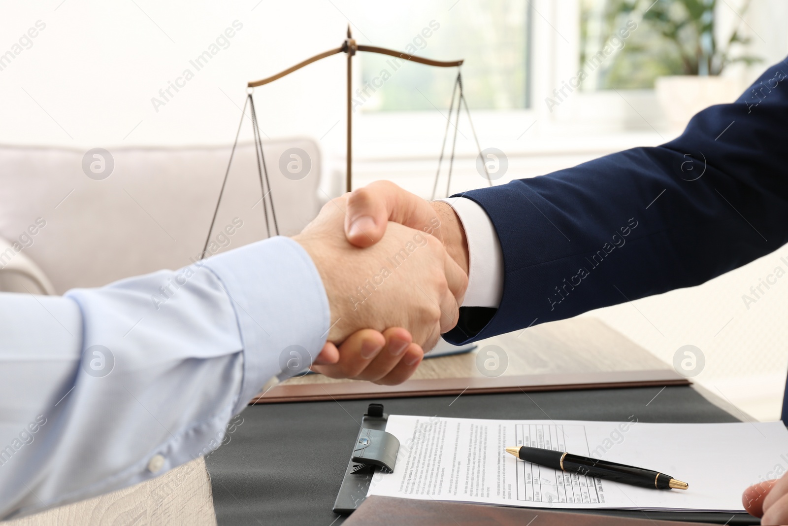 Photo of Lawyer handshaking with client over table in office, closeup