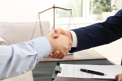 Photo of Lawyer handshaking with client over table in office, closeup