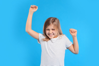 Photo of Excited little girl on light blue background