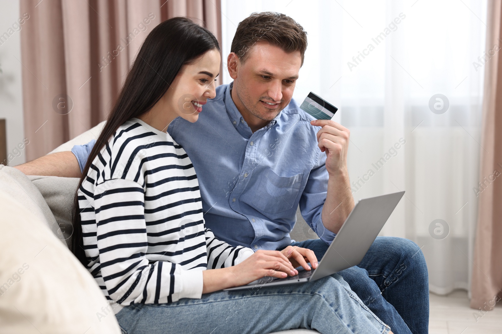 Photo of Happy couple with laptop and credit card shopping online together at home