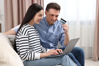 Photo of Happy couple with laptop and credit card shopping online together at home