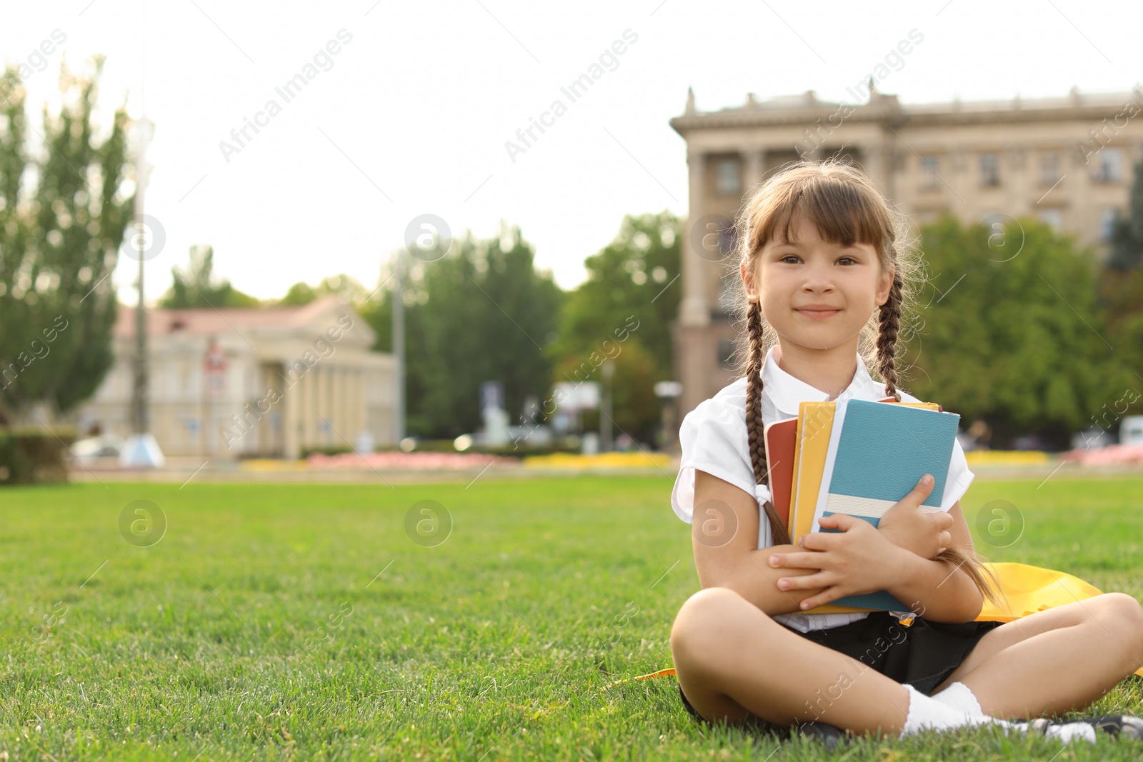 Photo of Schoolgirl with stationery sitting on grass outdoors