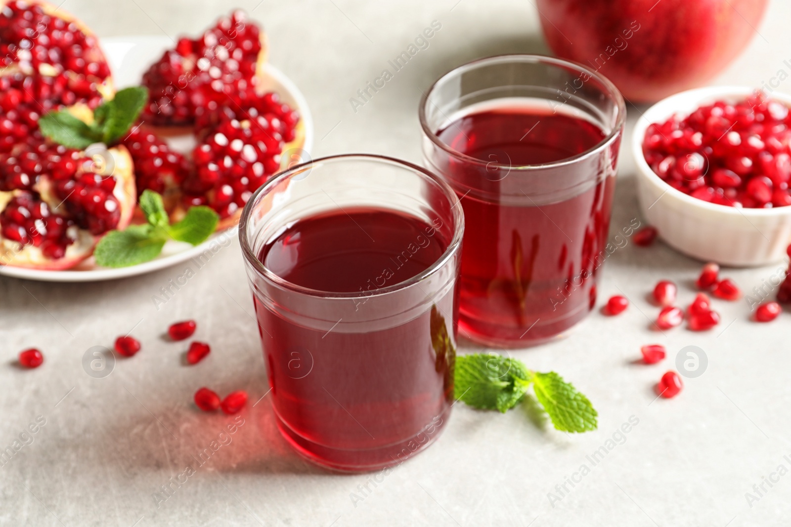 Photo of Composition with glasses of fresh pomegranate juice on table