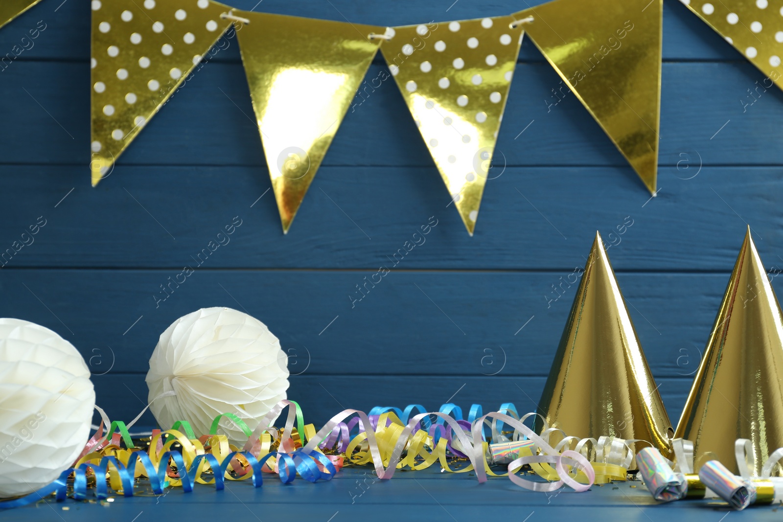 Photo of Colorful serpentine streamers and other party accessories on blue wooden table