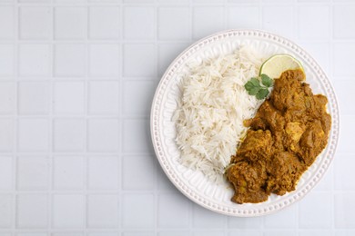 Photo of Delicious chicken curry with rice on white tiled table, top view. Space for text