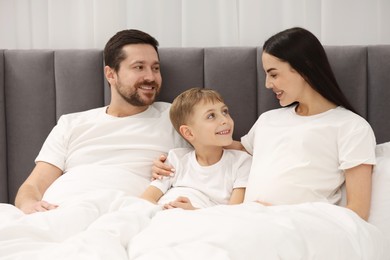 Photo of Happy pregnant woman with her son and husband in bed at home