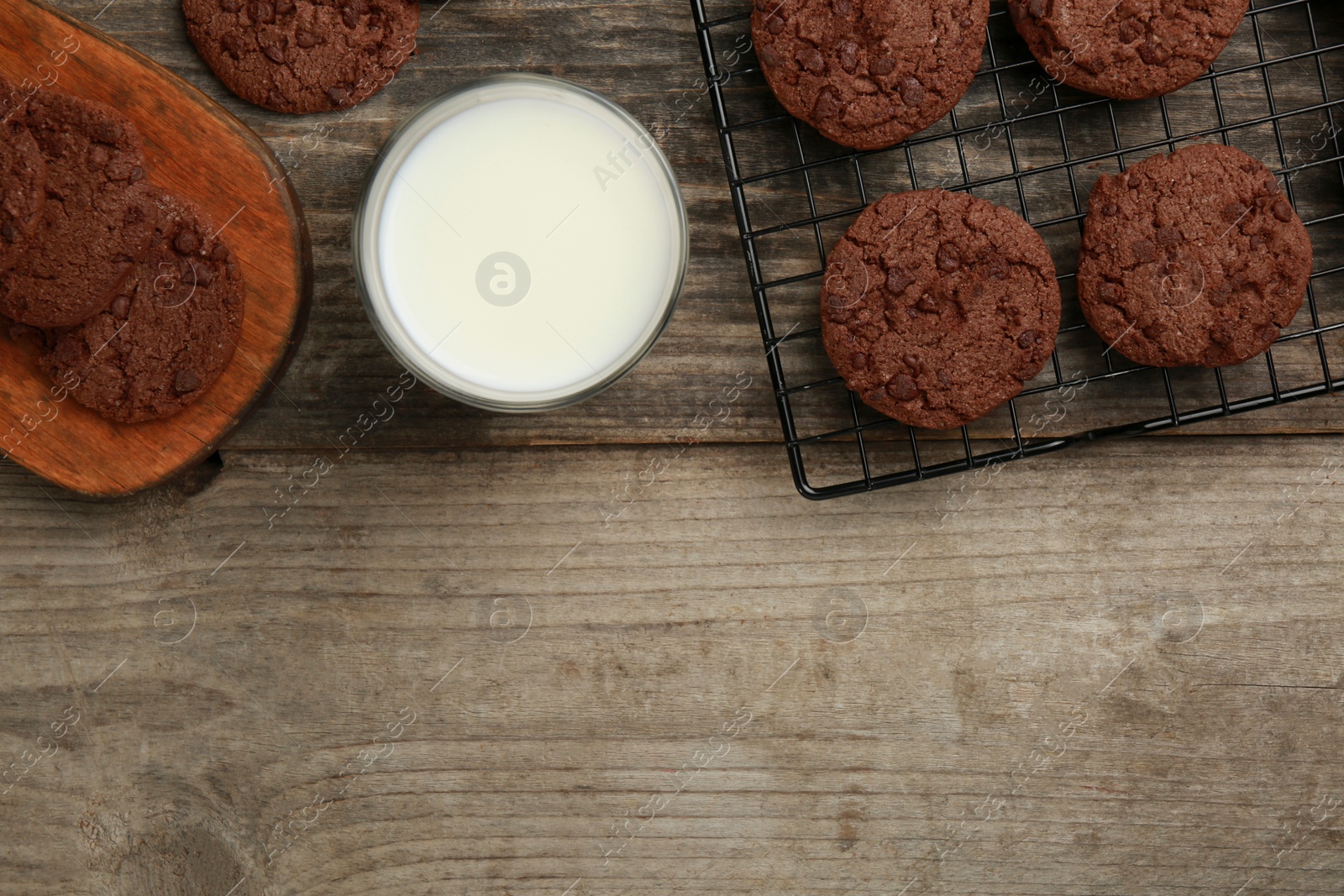 Photo of Delicious chocolate chip cookies and glass of milk on wooden table, flat lay. Space for text