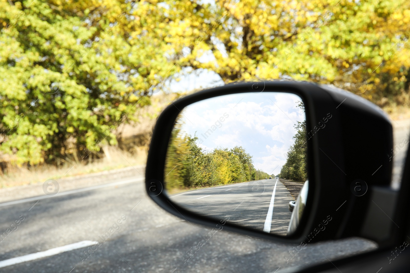 Photo of Closeup of car side rear view mirror on sunny day